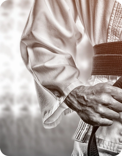 Close-up de um artista marcial a ajustar um cinto preto num uniforme tradicional de judô branco